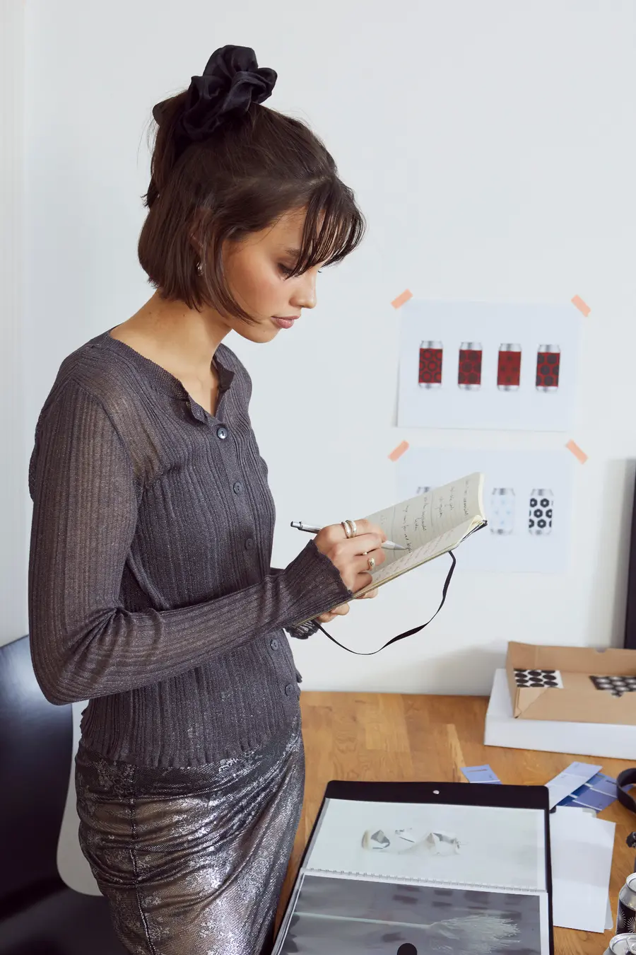 Woman writing notes beside a wall of design concepts